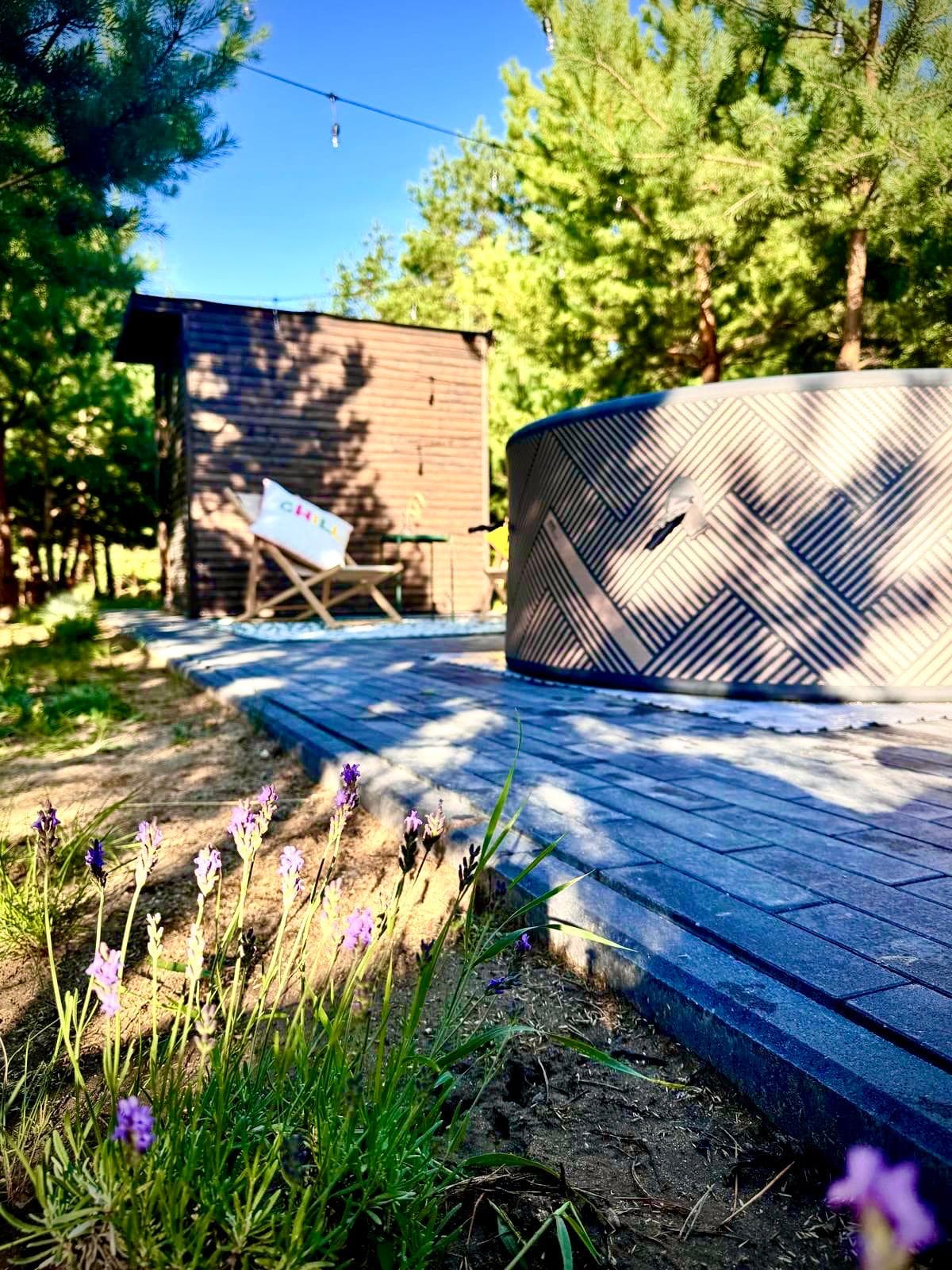 Jacuzzi na tarasie wśród sosen z leżakami i lawendą w tle